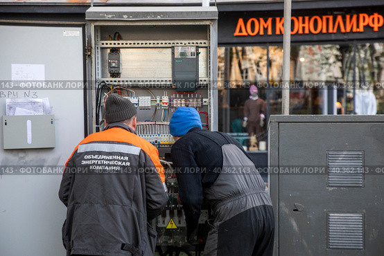 Сотрудники Объединенной электрической компании проверяют соединения в электрическом шкафу на Никитском бульваре в центре города Москвы, Россия (2023 год). Редакционное фото, фотограф Николай Винокуров / Фотобанк Лори
