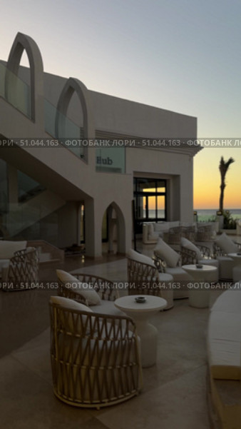 Современное здание с арочными элементами на фоне голубого неба The villa is a modern, white Mediterranean-style house with arched doorways, large balconies, and light stone elements, surrounded by a landscaped rocky garden and a clear blue sky. Стоковое видео, видеограф Zita Khasanova / Фотобанк Лори