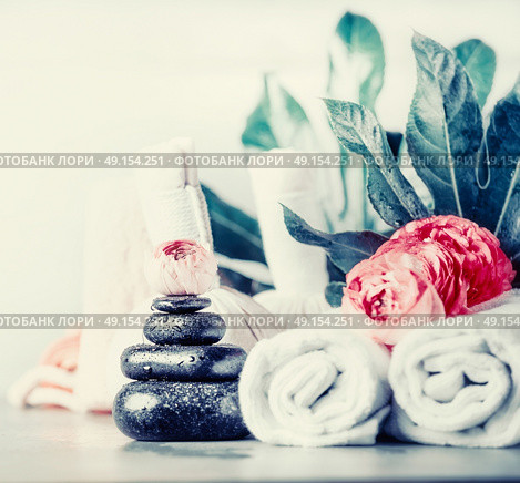 Spa setting with hot black basalt massage stones ,flowers , towels and palm leaves, front view, wellness concept. Стоковое фото, агентство Ingram Publishing / Фотобанк Лори