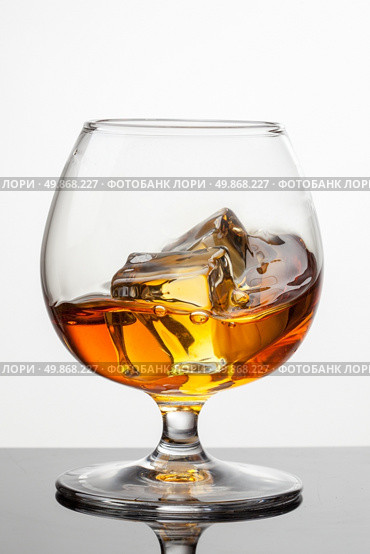Splash of whiskey with ice in glass isolated on white background. Raw image, no postproduction. Стоковое фото, агентство Ingram Publishing / Фотобанк Лори