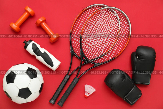 Sport equipment with rackets and boxing gloves on red background. Top view. Стоковое фото, фотограф Pixel_shot / Фотобанк Лори