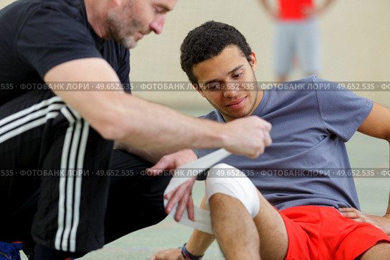 sports coach bandaging knee injury. Стоковое фото, агентство Ingram Publishing / Фотобанк Лори