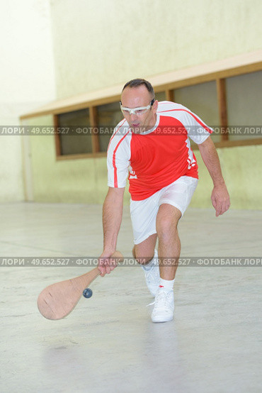 Sportsman reaching for ball with wooden racket. Стоковое фото, агентство Ingram Publishing / Фотобанк Лори