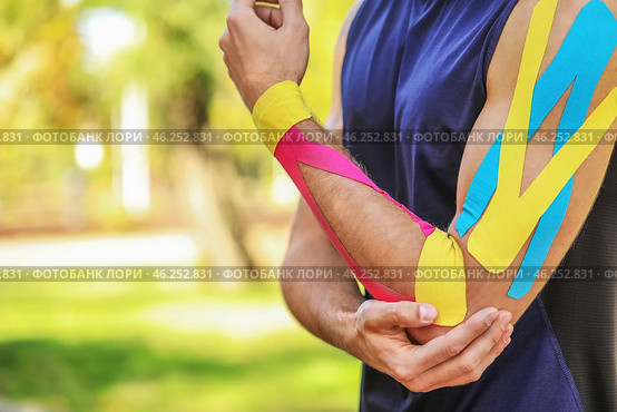 Sporty man with physio tape applied on arm outdoors, closeup. Стоковое фото, фотограф Pixel_shot / Фотобанк Лори