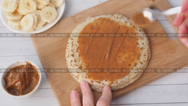 Spread thin pancakes with chocolate or cream paste. Pancakes with boiled condensed milk and banana filling. Стоковое видео, видеограф Глущенко Елена / Фотобанк Лори