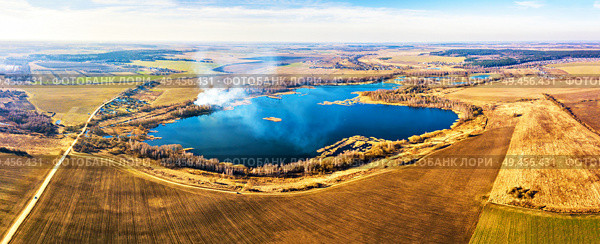 Spring agricultural fields. Smoke on the water and blue lake panorama. Winter crops and plowed field. Spring countryside aerial landscape. Dirt roads and village. Belarus. Стоковое фото, агентство Ingram Publishing / Фотобанк Лори