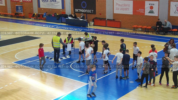 Sremska Mitrovica, Serbia 03.12.22: Children athletic competitions between school students. Boys and girls play sports. Gym. Kids stand in line for the long jump. Boy jumps. Coach records result (2022 год). Редакционное видео, видеограф Юлия Петровская / Фотобанк Лори