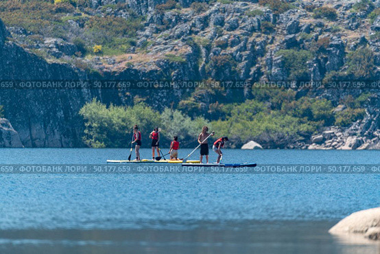 Stand up paddleboarding on lake. Watersport on lake. Tourist outdoor activity at Lagoa Comprida, Serra da Estrela National Park in Portugal. Стоковое фото, агентство Ingram Publishing / Фотобанк Лори