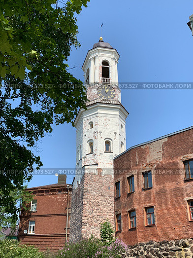 Старая Часовая  башня , бывшая колокольня, рядом с жилым домом из красного кирпича в городе Выборг на фоне голубого неба (2023 год). Стоковое фото, фотограф Елена Яворская / Фотобанк Лори