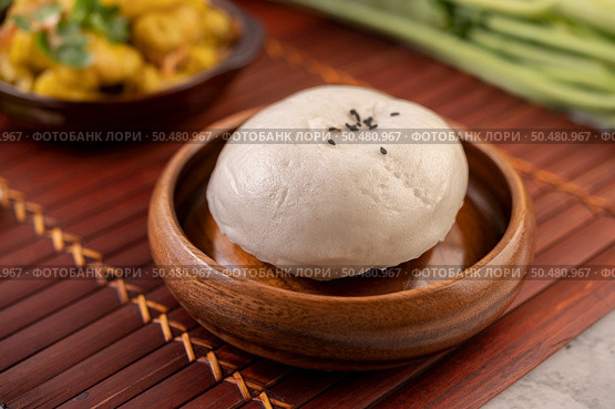 Steamed buns in a wooden dish on a wooden grill. Selective focus. Стоковое фото, агентство Ingram Publishing / Фотобанк Лори