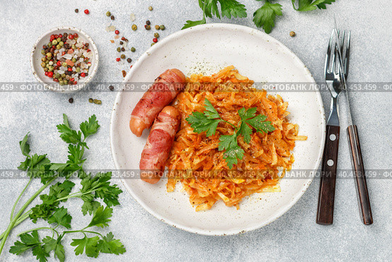 Stewed cabbage with carrots, onions and tomatoes and sausages in bacon with parsley and spices in a white plate. Bigos. Delicious lunch. Стоковое фото, фотограф Виктория Панченко / Фотобанк Лори