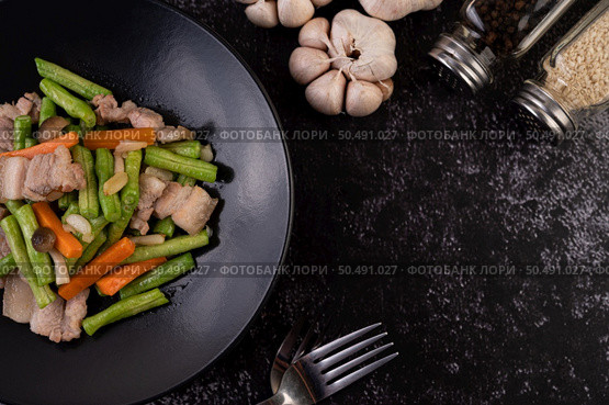 Stir-fried long beans and carrots, add pork belly, put on a black plate. Стоковое фото, агентство Ingram Publishing / Фотобанк Лори