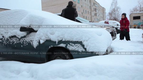 Стоянка во дворе жилого дома с занесенными снегом автомобилями и семья с детьми, чистящая свой автомобиль. Стоковое видео, видеограф Кекяляйнен Андрей / Фотобанк Лори