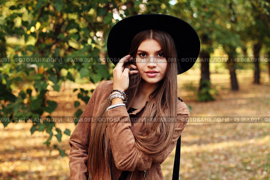 Street fashion concept - closeup portrait of a pretty girl. Wearing hat and suede jacket holding bag with fringe. Beautiful autumn woman. . Стоковое фото, агентство Ingram Publishing / Фотобанк Лори