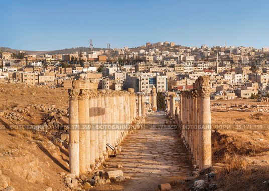 Street South Decumanus in the ancient greco-roman city of Gerasa and the modern city Jerash in the background, Jordan (2016 год). Стоковое фото, фотограф Наталья Волкова / Фотобанк Лори