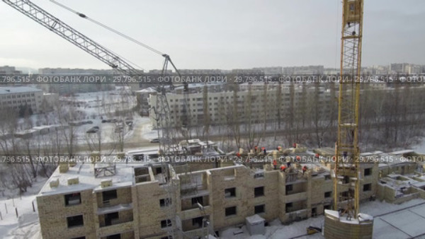 Строительство многоэтажного здания в зимний период. Вид с воздуха. Construction of a multi-storey building in winter. Aerial view. (2019 год). Стоковое видео, видеограф Евгений Романов / Фотобанк Лори