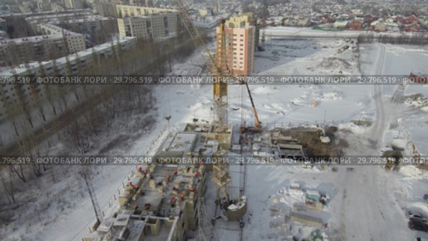 Строительство многоэтажного здания в зимний период. Вид с воздуха. Construction of a multi-storey building in winter. Aerial view. (2019 год). Стоковое видео, видеограф Евгений Романов / Фотобанк Лори