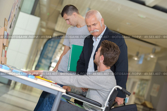 student in wheelchair talking with classmate in library. Стоковое фото, агентство Ingram Publishing / Фотобанк Лори