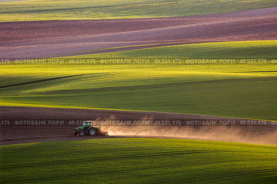 Sunset light over plowing tractor in the spring, South Moravia, Czech Republic. tractor plows the field in the spring. Стоковое фото, агентство Ingram Publishing / Фотобанк Лори