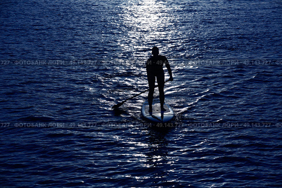 SUP Stand up Surf girl with paddle at sunset. Стоковое фото, агентство Ingram Publishing / Фотобанк Лори
