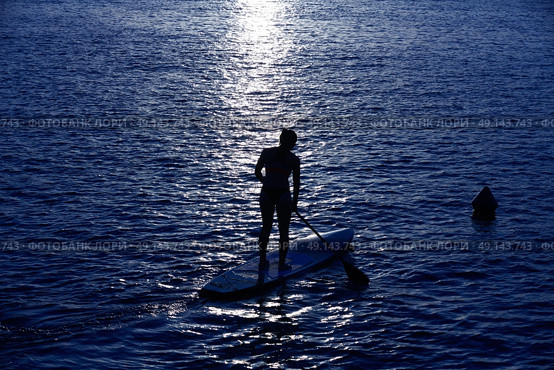SUP Stand up Surf girl with paddle at sunset. Стоковое фото, агентство Ingram Publishing / Фотобанк Лори