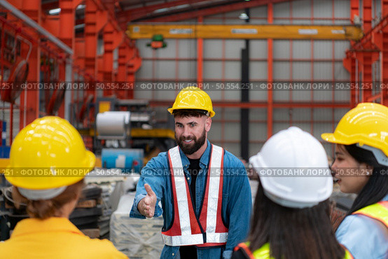 Supervisor and group of factory workers wearing hard hats meeting brief together before starting the day’s work. Стоковое фото, агентство Ingram Publishing / Фотобанк Лори