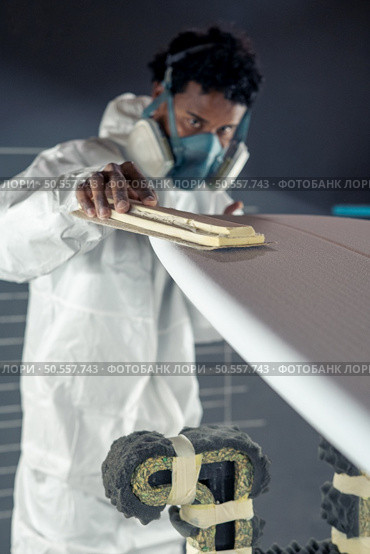 Surfboard manufacturing, Shaper working on board details. Concept of industrial manufacturing, qualified professional, occupation and employment. Стоковое фото, агентство Ingram Publishing / Фотобанк Лори