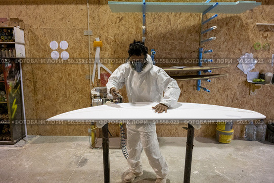 Surfboard manufacturing, Shaper working on board details. Concept of industrial manufacturing, qualified professional, occupation and employment. Стоковое фото, агентство Ingram Publishing / Фотобанк Лори