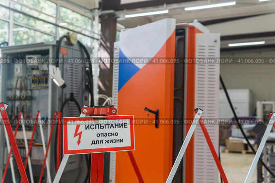 Табличка с надписью Испытание! Опасно для жизни! на ограждении на фоне размытого электрооборудования в цехе. Стоковое фото, фотограф Евгений Харитонов / Фотобанк Лори
