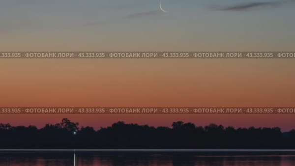 Таймлапс. Восход месяца на красно-оранжевом небе на восходе в утренних сумерках с озером на переднем плане. Природное небо. Фон, золотистое небо на горизонте, великолепное облако на рассвете, сумеречное небо. Стоковое видео, видеограф Владимир Глинский / Фотобанк Лори