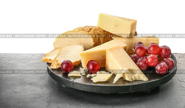 Тарелка с кусочками вкусного сыра пармезан, виноград и хлеб на столе на белом фоне. Стоковое фото, фотограф Pixel_shot / Фотобанк Лори
