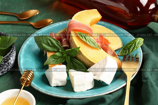 Тарелка с вкусным дыней, прошутто, сыром и базиликом на цветном фоне, крупным планом. Стоковое фото, фотограф Pixel_shot / Фотобанк Лори