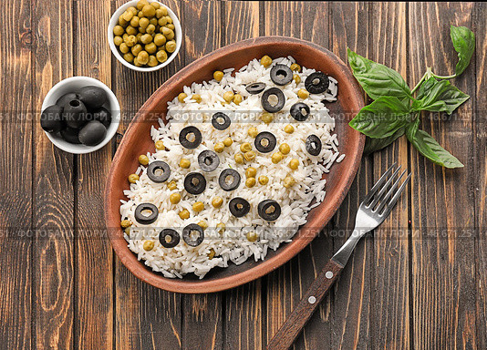 Тарелка с вкусным отварным рисом, оливками и горохом на деревянном столе. Стоковое фото, фотограф Pixel_shot / Фотобанк Лори