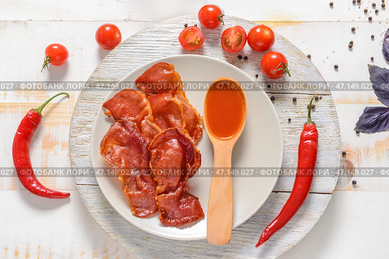 Тарелка с вкусным жареным беконом и соусом на столе. Стоковое фото, фотограф Pixel_shot / Фотобанк Лори