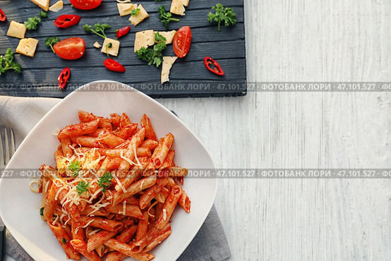 Тарелка вкусной пасты пенне с томатным соусом на деревянном столе. Стоковое фото, фотограф Pixel_shot / Фотобанк Лори