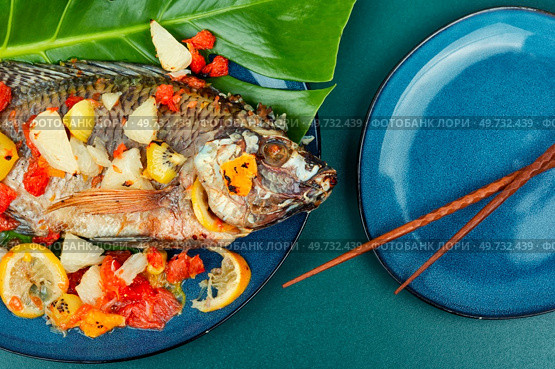 Tasty large grilled tilapia fish with fruit. Popular Malay or Indonesian food.. Roasted whole tilapia with citrus sauce. Стоковое фото, агентство Ingram Publishing / Фотобанк Лори