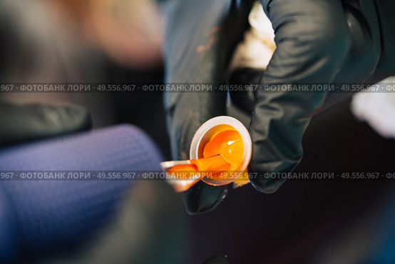 Tattoo woman loading the tattoo machine with orange ink. Tattoo concept.. Tattoo woman loading the tattoo machine with ink. Стоковое фото, агентство Ingram Publishing / Фотобанк Лори