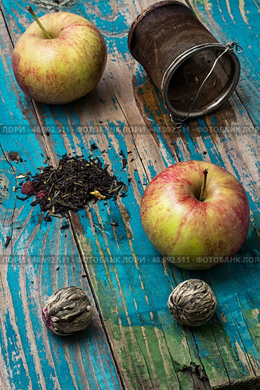 tea leaves and red apple on wooden background.The image is tinted in vintage style. tea leaves and red apple on wooden background. Стоковое фото, агентство Ingram Publishing / Фотобанк Лори