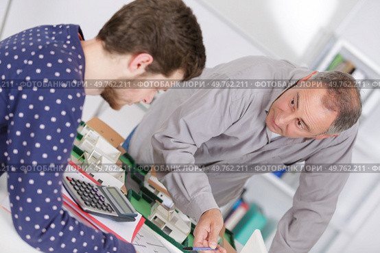 teacher in business school checking coursework of student. Стоковое фото, агентство Ingram Publishing / Фотобанк Лори