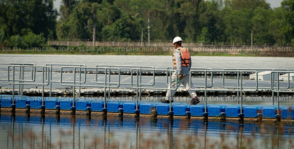 Technician currently evaluating and repairing the transmission terminals for electricity generated by solar energy in a floating solar power system. Стоковое фото, агентство Ingram Publishing / Фотобанк Лори
