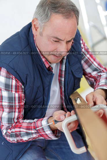 technician fixing lock in door with screwdriver at home. Стоковое фото, агентство Ingram Publishing / Фотобанк Лори