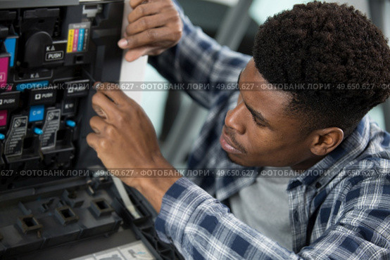 technician tries to repair a printer. Стоковое фото, агентство Ingram Publishing / Фотобанк Лори