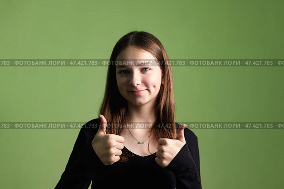 Teen Girl Expresses Excitement in Studio Setting With Green Background and Positive Vibes. Стоковое фото, фотограф Aleksandr Golubev / Фотобанк Лори