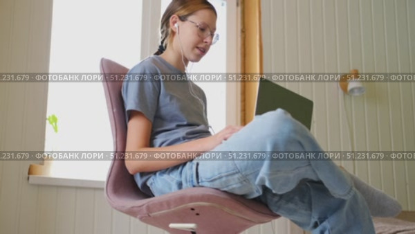 Teen girl school student wear headphones watching online webinar, talking through webcam looking at laptop. Teenager conducting video conference on computer at home, chatting online with friends. 4K. Стоковое видео, видеограф Марина Демидюк / Фотобанк Лори