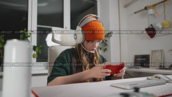 Teenage gamer enjoys gaming on smartphone, highlighting evolution of portable gaming devices. With intense focus explores virtual world of mobile esports. Gadgets and focus elevate gaming experience. Стоковое видео, видеограф Енваев Андрей / Фотобанк Лори