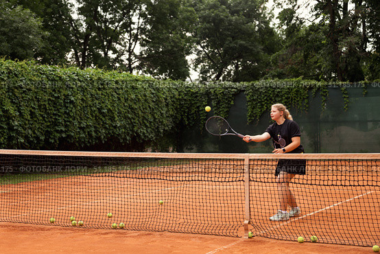 Teenage Girl Practicing Tennis Skills on a Clay Court Surrounded by Nature. Стоковое фото, фотограф Aleksandr Golubev / Фотобанк Лори