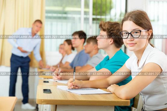 Teenage students studying in classroom with teacher, writing lectures. Стоковое фото, фотограф Яков Филимонов / Фотобанк Лори