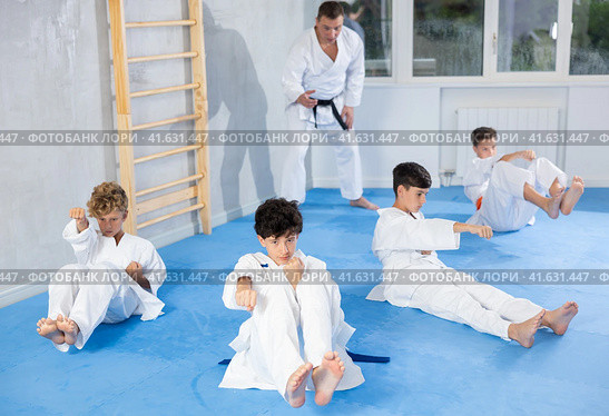 Teenagers performing core twist with simultaneous punches during martial arts training. Стоковое фото, фотограф Яков Филимонов / Фотобанк Лори