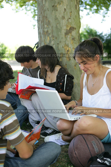 Teens sat by a tree studying. Стоковое фото, агентство Ingram Publishing / Фотобанк Лори