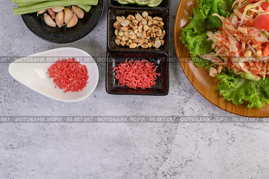 Thai papaya salad on salad in a wooden plate with Yardlong beans and garlic, Top view. Стоковое фото, агентство Ingram Publishing / Фотобанк Лори